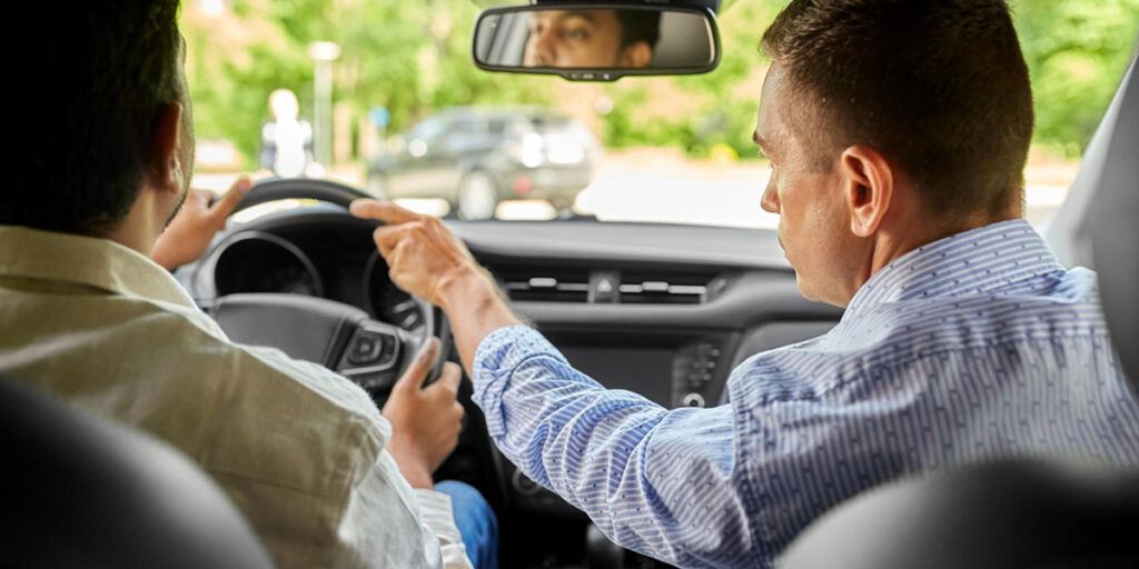 Dual control car driving lesson with instructor ensuring safety